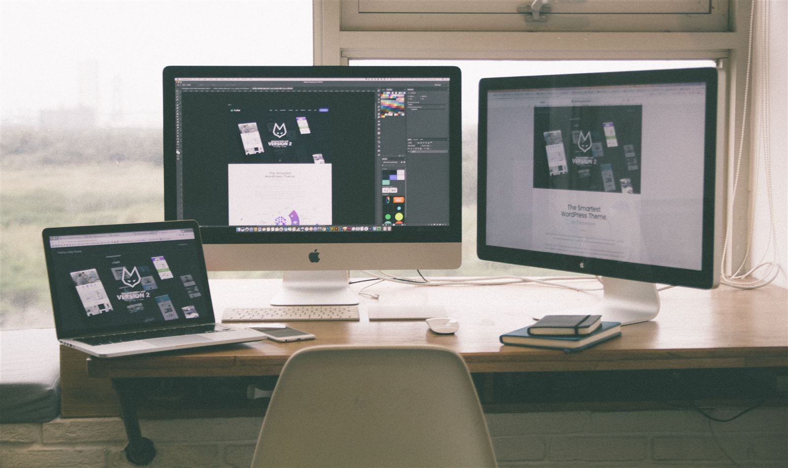 Website design and development workspace with a laptop and two desktop monitors